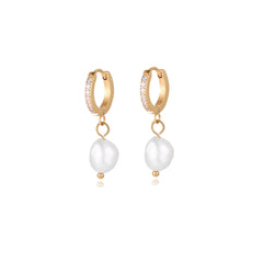 Gold huggie hoop earrings with pavé crystals and white freshwater pearl drops on cream background