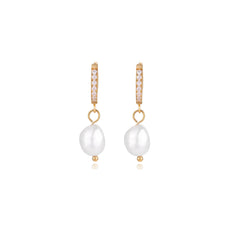 Gold huggie hoop earrings with pavé crystals and white freshwater pearl drops on cream background