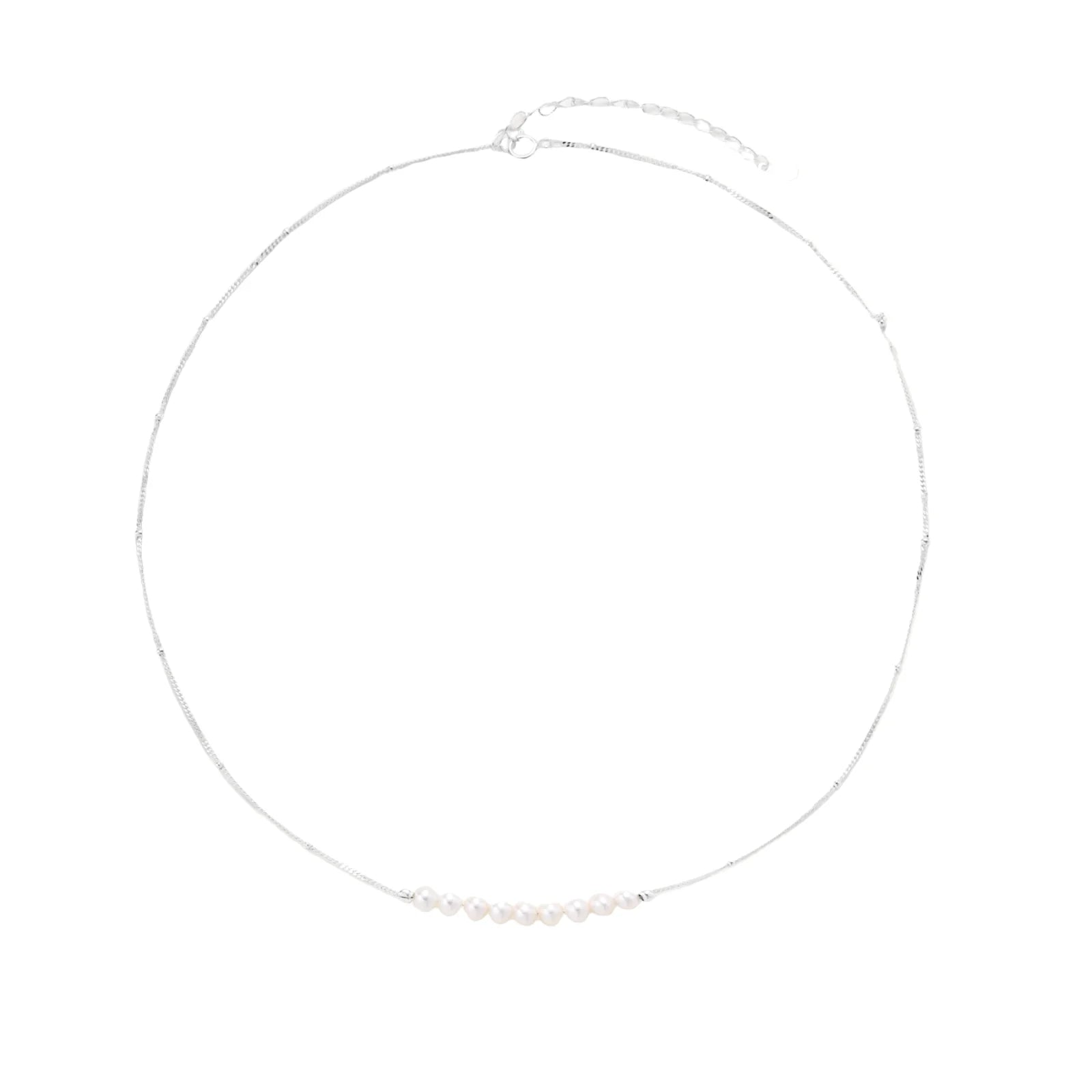 Delicate sterling silver chain necklace with small freshwater pearls arranged in a curved smile arc on cream background.
