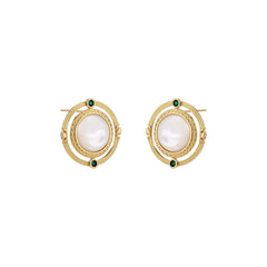 Circular gold stud earrings with iridescent mother-of-pearl center and green zirconia accents on cream background.