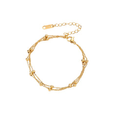 Three-strand gold-plated bracelet with clustered ball beads and adjustable clasp on cream background