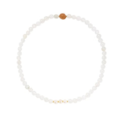Three layered white beaded bracelets with carved orange agate lotus centerpiece and freshwater pearls on cream background.