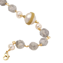 Bracelet with cloudy quartz beads, freshwater pearls, and gold-wrapped baroque pearl centerpiece on white background.