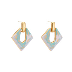 Geometric square enamel earrings with marbled turquoise and lavender pattern, gold U-shaped connector on cream background.